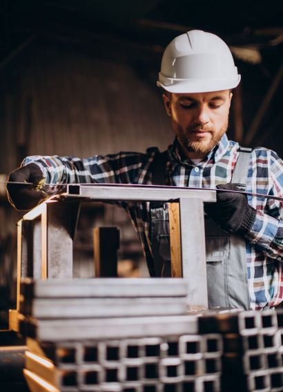 Workman wearing har hat with measuring ruler at factory
